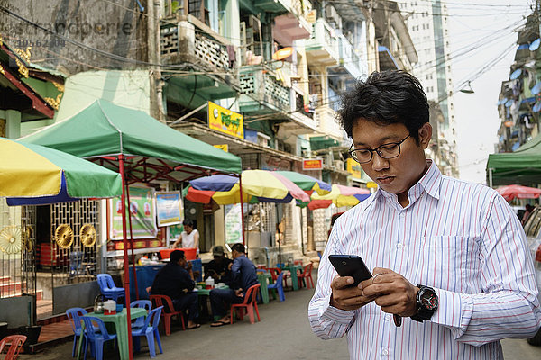 Asiatischer Geschäftsmann benutzt Mobiltelefon in der Stadt