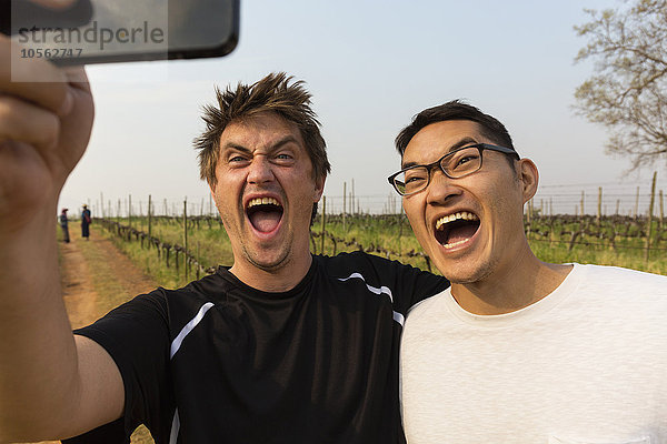 Männer nehmen Selfie mit Handy im Weinberg