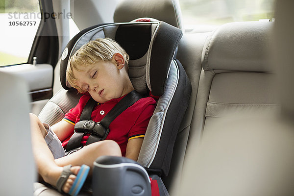 Kaukasischer Junge schläft im Autositz