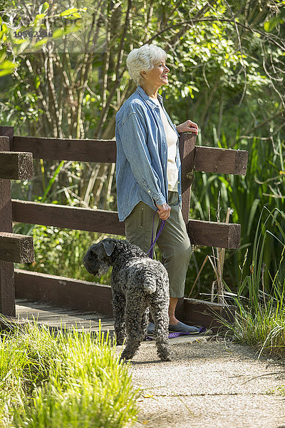 Ältere kaukasische Frau geht mit Hund im Park spazieren