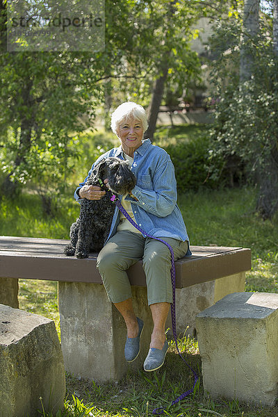 Ältere kaukasische Frau umarmt Hund im Park