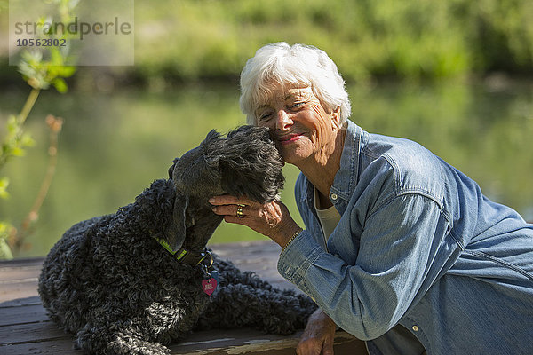 Ältere kaukasische Frau umarmt Hund im Park