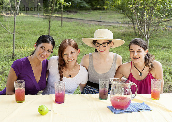 Frauen trinken Saft im Freien am Tisch