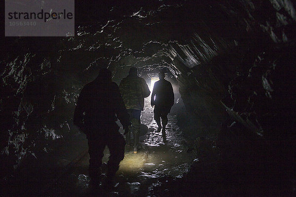 Männer gehen in dunkler Höhle