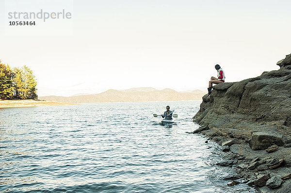 Frau beobachtet Freund beim Rudern im Kajak auf dem See