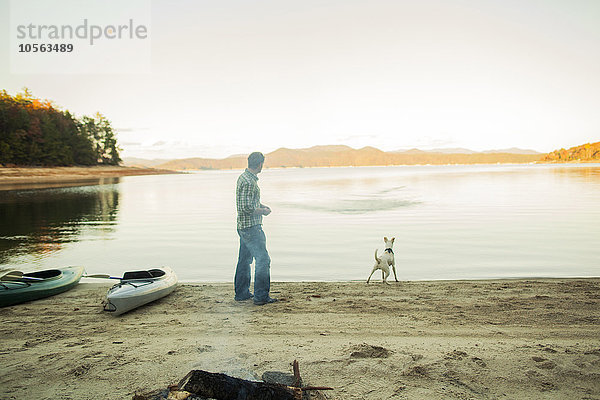 Mann und Hund spielen in einem abgelegenen See