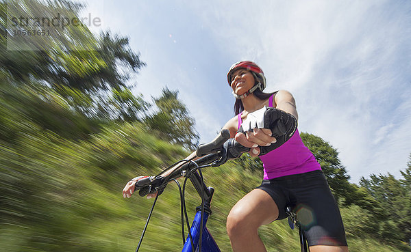 Hispanische Frau fährt Fahrrad im Freien