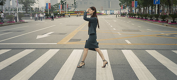Chinesische Geschäftsfrau auf dem Fußgängerüberweg