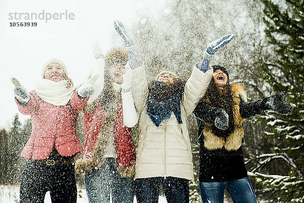 Kaukasische Mädchen  die Schnee in die Luft werfen