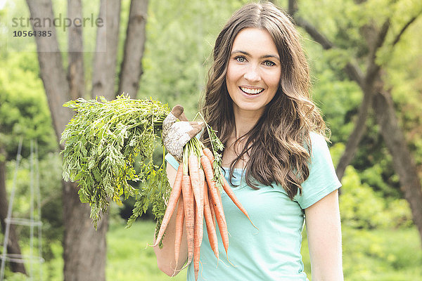 Kaukasische Frau hält Karotten im Garten