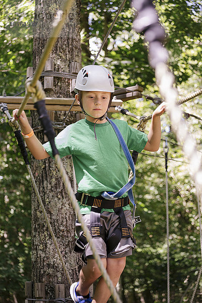Kaukasischer Junge balanciert auf einer Seilbrücke