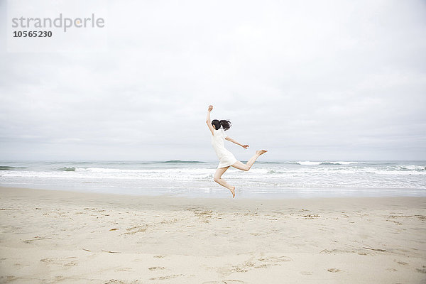 Vor Freude springende Frau am Strand