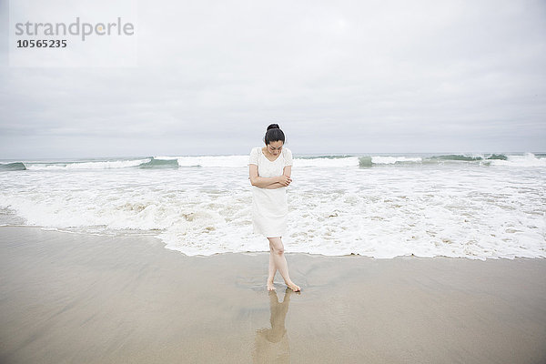 Frau steht in der Nähe von Wellen am Strand