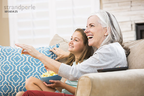 Kaukasische Großmutter und Enkelin sehen auf dem Sofa fern