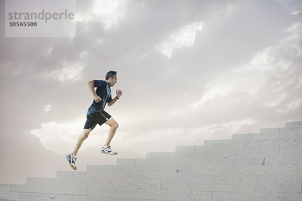 Gemischtrassiger Mann joggt auf Stufen