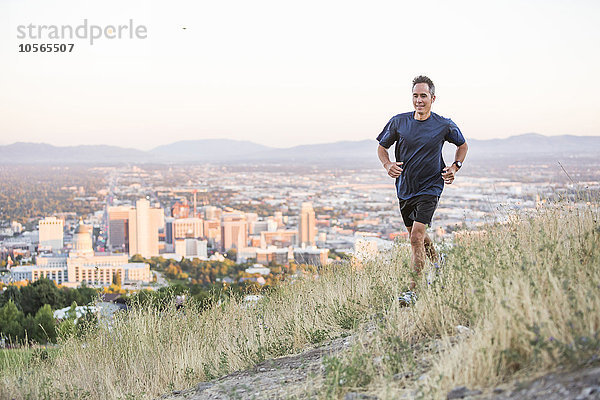 Gemischtrassiger Mann  der auf einer Bergkuppe über Salt Lake City  Utah  Vereinigte Staaten  läuft
