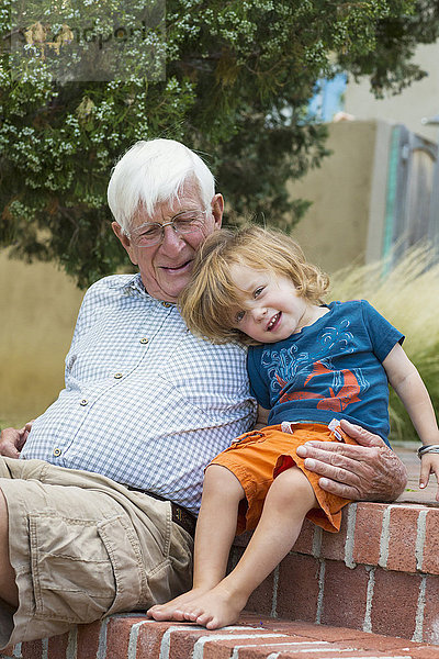 Kaukasischer Großvater und Enkel umarmen sich im Freien