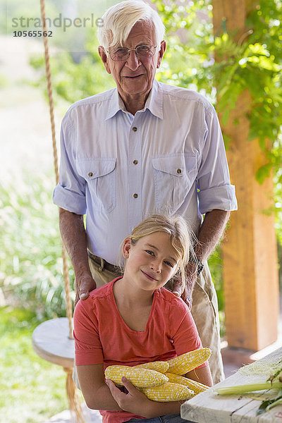 Kaukasischer Großvater und Enkelin beim Maisschälen