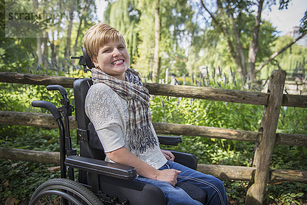 Querschnittsgelähmte Frau im Rollstuhl lächelt im Garten