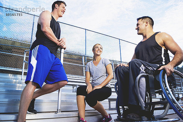 Querschnittsgelähmter Sportler im Rollstuhl mit Freunden auf der Tribüne