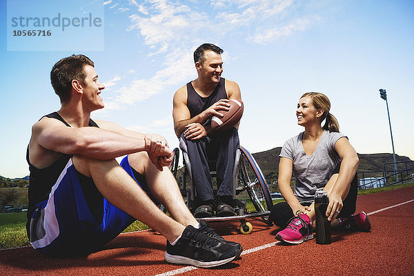 Querschnittsgelähmte Athletin im Rollstuhl und Freunde auf der Strecke
