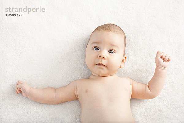 Nacktes gemischtrassiges Baby liegt auf einer Decke