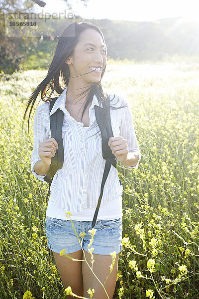 Gemischtrassige Frau trägt Rucksack im Feld