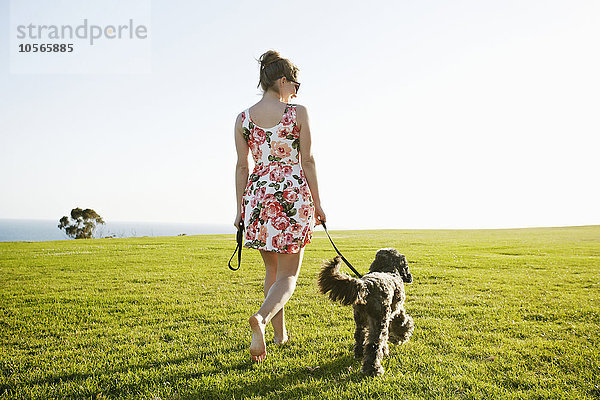 Kaukasische Frau geht mit Hund im Feld spazieren