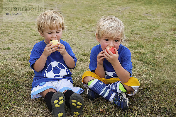 Kaukasische Fußballspieler essen Äpfel