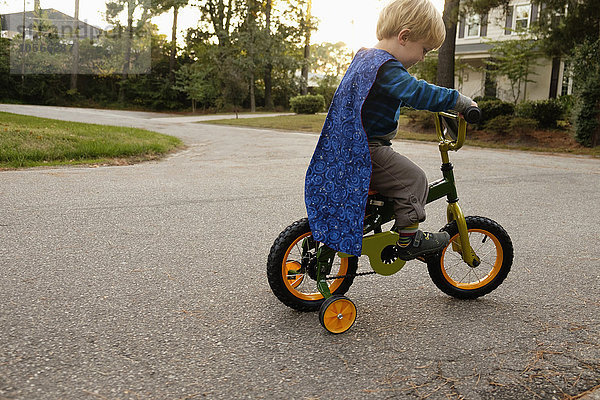 Kaukasischer Junge fährt Fahrrad mit Stützrädern