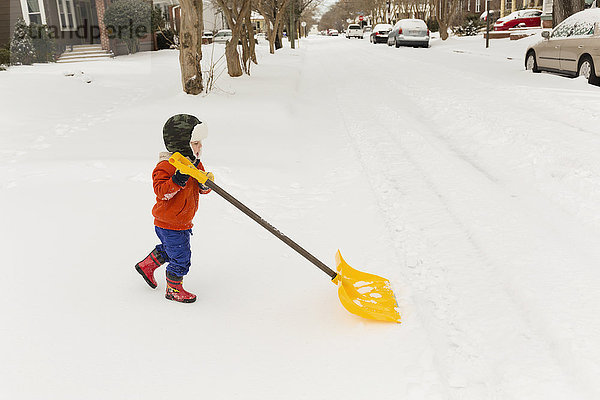 Kaukasischer Junge beim Schneeschaufeln