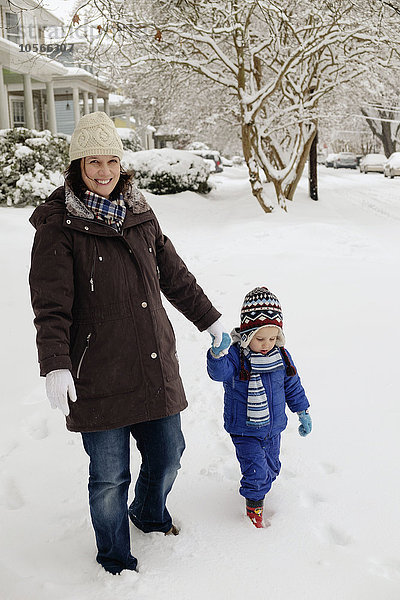 Kaukasische Mutter und Sohn gehen im Schnee spazieren