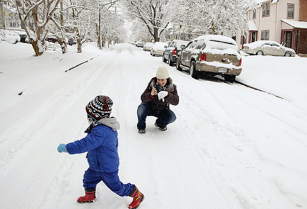 Kaukasische Mutter und Sohn spielen im Schnee