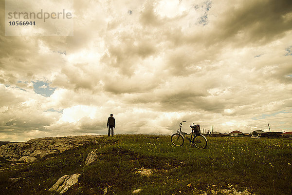 Kaukasischer Mann mit Fahrrad auf einem Feld