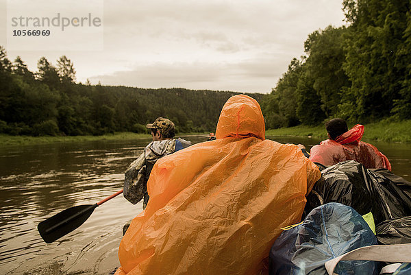 Menschen mit Ponchos auf einem Boot im Fluss