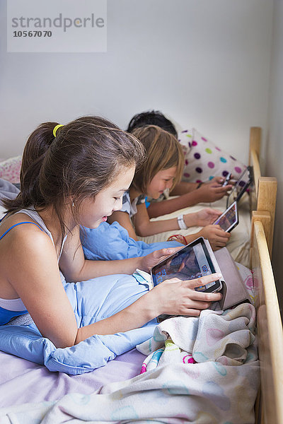 Mädchen benutzen digitale Tablets im Bett