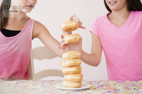 Kaukasische Zwillingsschwestern essen Donuts