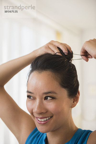 Chinesische Frau bindet ihr Haar zu einem Dutt