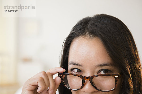 Chinesische Frau  die über eine Brille schaut