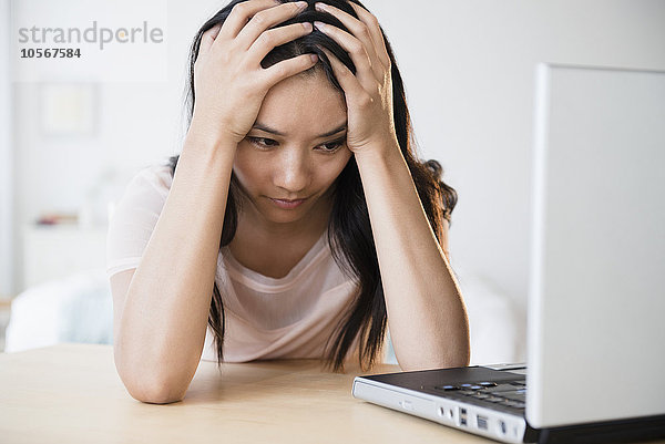 Frustrierte chinesische Frau mit Laptop