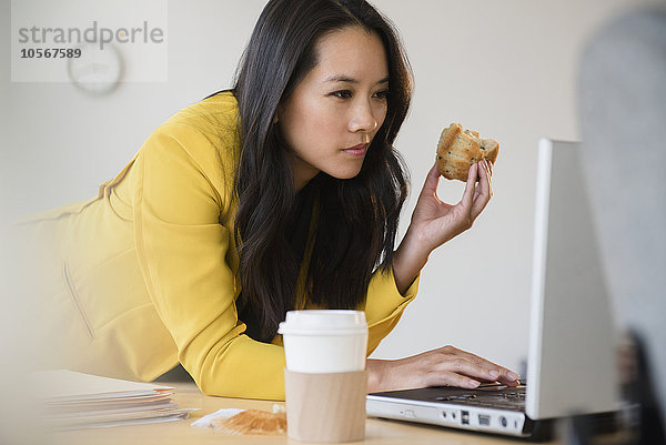 Chinesische Geschäftsfrau mit Laptop und Essen