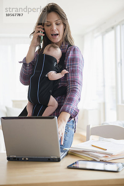 Mutter arbeitet zu Hause mit neuer kleiner Tochter