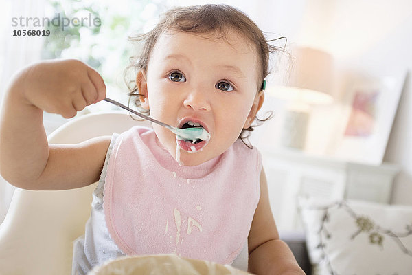 Gemischtrassiges Babymädchen isst Joghurt