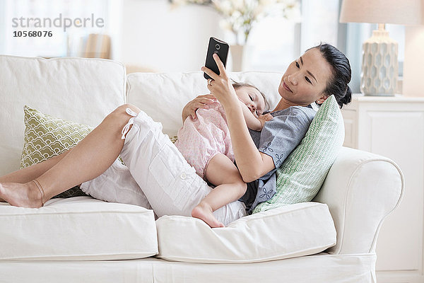 Mutter und kleine Tochter benutzen ein Mobiltelefon