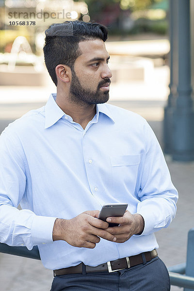 Indischer Geschäftsmann benutzt Mobiltelefon in der Stadt