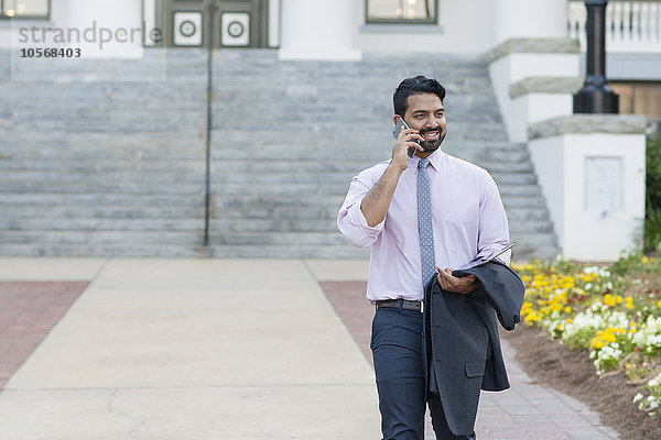 Indischer Geschäftsmann telefoniert auf dem Bürgersteig