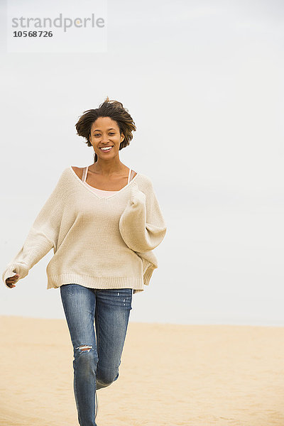 Afroamerikanische Frau läuft am Strand