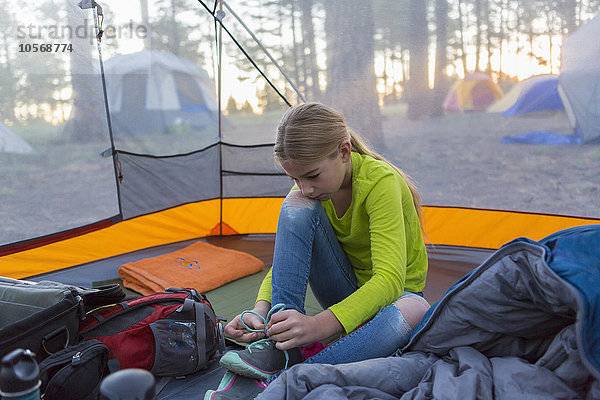 Kaukasisches Mädchen bindet Schuhe im Campingzelt