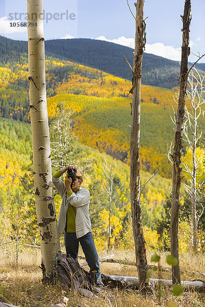 Mann beim Fotografieren mit Kamera im Herbstwald