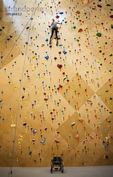 Querschnittsgelähmte Frau klettert in der Turnhalle